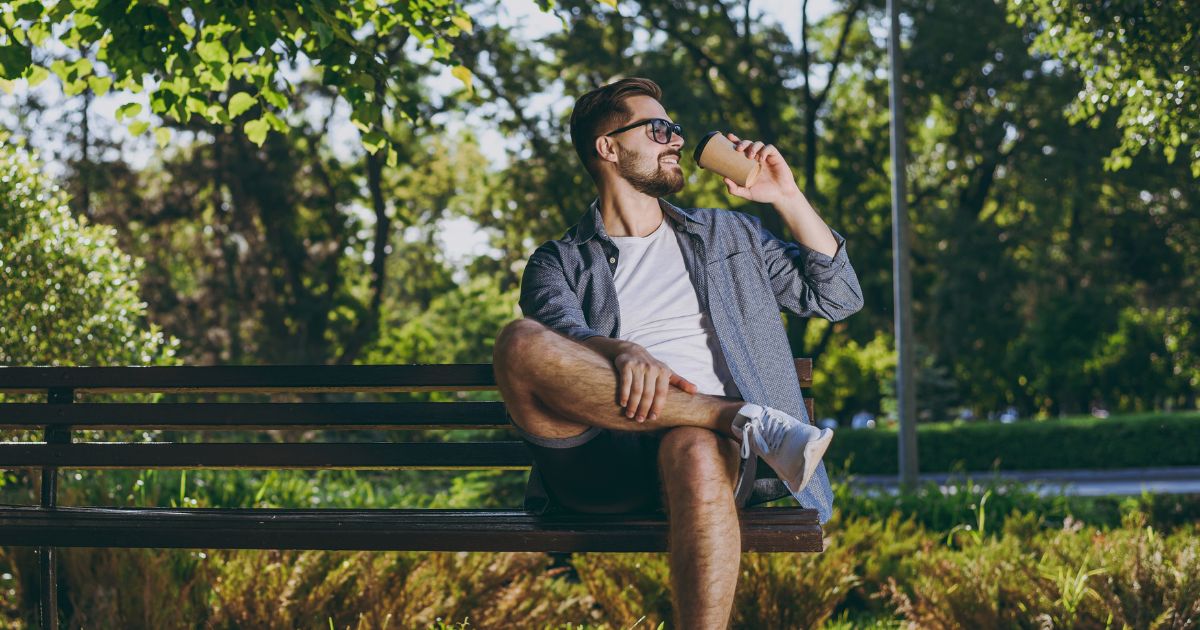 A man sitting on a bench having coffee in Begen County, NJ after a a TMS session for quiting smoking.